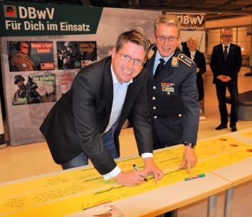 Stephan Stracke (links) unterzeichnet die „gelben Bänder der  Verbundenheit“ mit Hauptmann Andreas Steinmetz, 2. Stellvertreter des  Vorsitzenden des Deutschen BundeswehrVerband. ©Büro Stracke, MdB